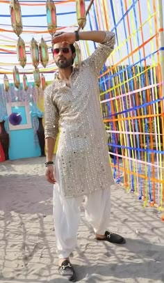 a man standing in front of a colorful wall with lots of lights hanging from it