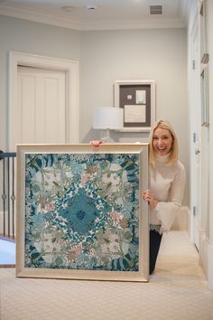 a woman is holding up a quilt in front of the camera and smiling at the camera