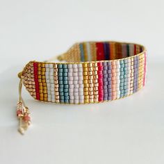 a multicolored beaded bracelet with a tassel on the end is shown