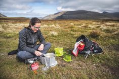 a woman sitting on the ground next to a backpack and some food in front of her