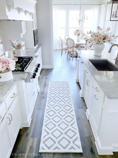 a kitchen with white cabinets and flowers on the counter top in front of an oven