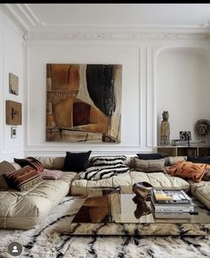 a living room filled with lots of furniture next to a painting on the wall above a coffee table