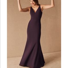 a woman in a long purple dress with her arms up and one hand raised to the side