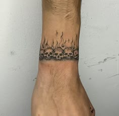 a man's hand with a tattoo on it that has skulls and flames coming out of it