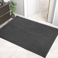 a black door mat on the floor next to a dresser