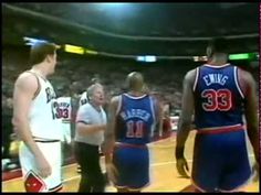 two basketball players talking to each other in front of an audience at a game with the referee looking on