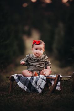 a baby sitting on top of a wooden rocking chair in the middle of a field