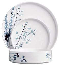 a white plate with blue flowers and leaves on the rim, next to a bowl