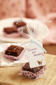 some brownies are wrapped in plastic and sitting on a wooden table next to a plate