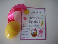 a pink and yellow plastic easter egg next to a paper tag on a white surface