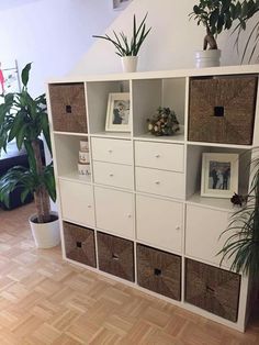 a white shelf filled with lots of baskets and plants next to a potted plant