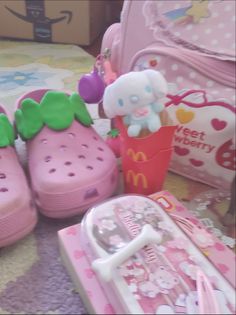 hello kitty shoes and other items are on the floor next to a pink suitcase,