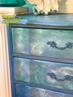 an old dresser has been painted with blue and green paint, as well as flowers