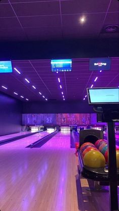 a bowling alley filled with lots of colorful bowling balls and neon lights on the ceiling