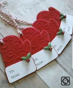 three red heart shaped tags with holly on them