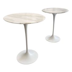 two tables with marble top and white bases, one on each side by the other