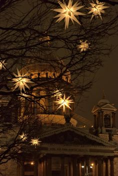 the building is lit up at night with snowflakes hanging from it's roof