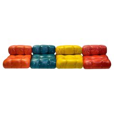 four different colored leather couches sitting next to each other on a white background,