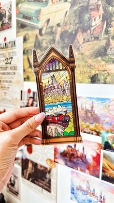 a person holding up a stained glass piece in front of a wall with pictures on it