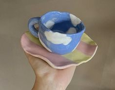 a hand holding a blue and white cup on top of a saucer