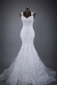 a white wedding dress on display in front of a gray background