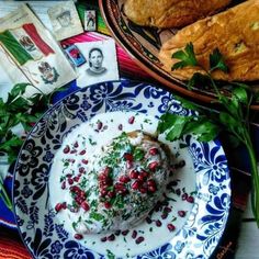 a blue and white plate topped with food on top of a table next to bread