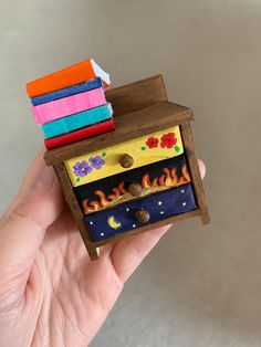 a hand holding a miniature wooden toy with fire and flames on it's side