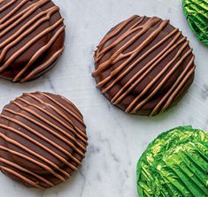 chocolate covered cookies sitting on top of a marble counter next to green foil wrapped cookies