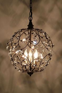 a decorative light fixture with crystal beads and leaves on the top, hanging from a ceiling