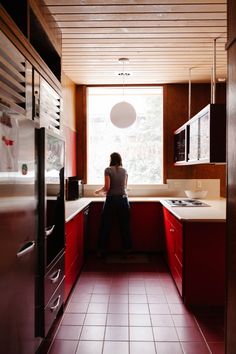 a woman standing in a kitchen with red cabinets