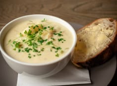 a white bowl filled with soup next to a piece of bread on top of a plate