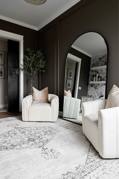 a living room with two white couches and a large round mirror in the corner