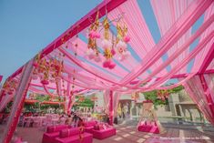 an outdoor wedding setup with pink couches and chandeliers