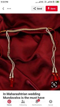 a white beaded necklace with red tassels on a maroon satin fabric background