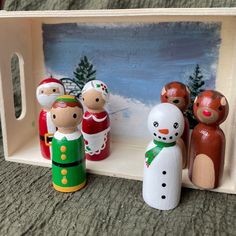 a group of wooden toy figurines sitting on top of a table next to a painting