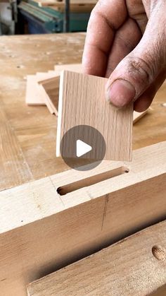 a person holding a piece of wood in their hand and pressing it on the board