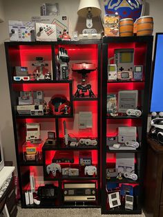 a room filled with lots of electronic devices and games on top of glass shelves in front of a flat screen tv