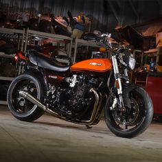 an orange and black motorcycle parked in front of a metal rack filled with other items