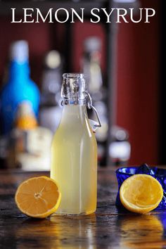 a bottle of lemon syrup sitting on top of a table next to two slices of lemon