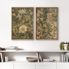 two floral paintings hang on the wall above a white shelf with books and vases