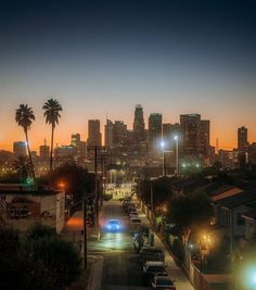 the city skyline is lit up at night, with cars parked on the side of the road