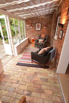 a living room with brick walls and flooring in the center, two couches are facing each other