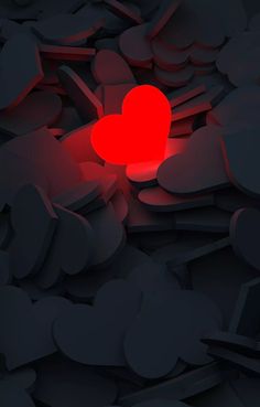 a red heart sitting in the middle of some black rocks and gravel with it's light on