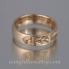 a gold wedding ring with leaves on the side and an engraved design in the middle