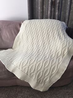 a white blanket sitting on top of a couch next to a brown sofa cushion and window