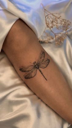 a woman's arm with a dragonfly tattoo on it