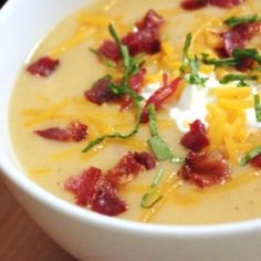 a close up of a bowl of soup with bacon and cheese in it on a table