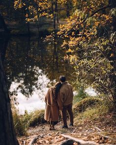 a man and woman standing next to each other in the woods