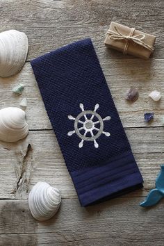 a towel with a ship wheel on it next to seashells