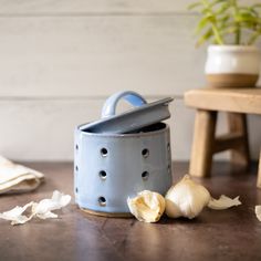 garlic cloves are sitting on the table next to a blue pot with lid